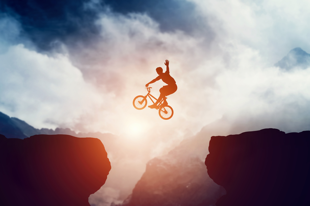 Man on mountain bike jumps over precipice